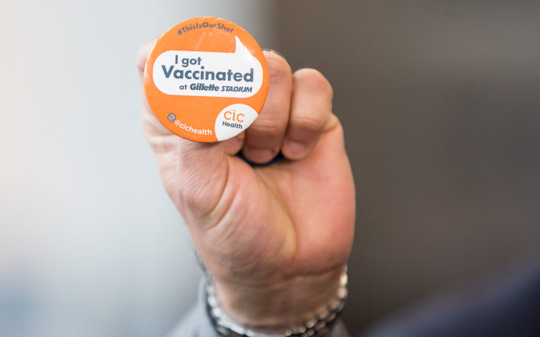 Person holding up a button as proof of receiving a COVID-19 vaccine.