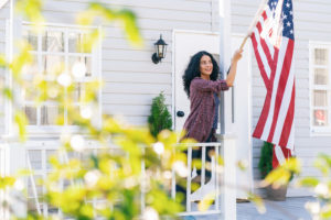 Woman hangs an American flag on her porch and celebrating Flag Day