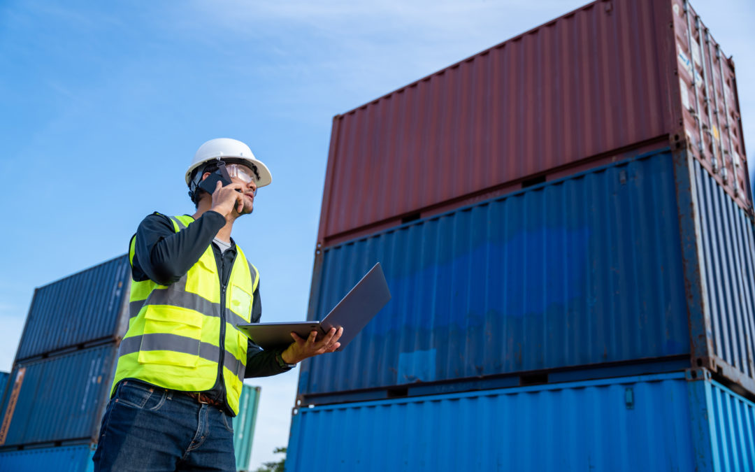 Man who works in supply chain logistics oversees containers in a port. Labor shortages in the trucking industry are making it difficult to pick up and deliver products that arrive at ports.